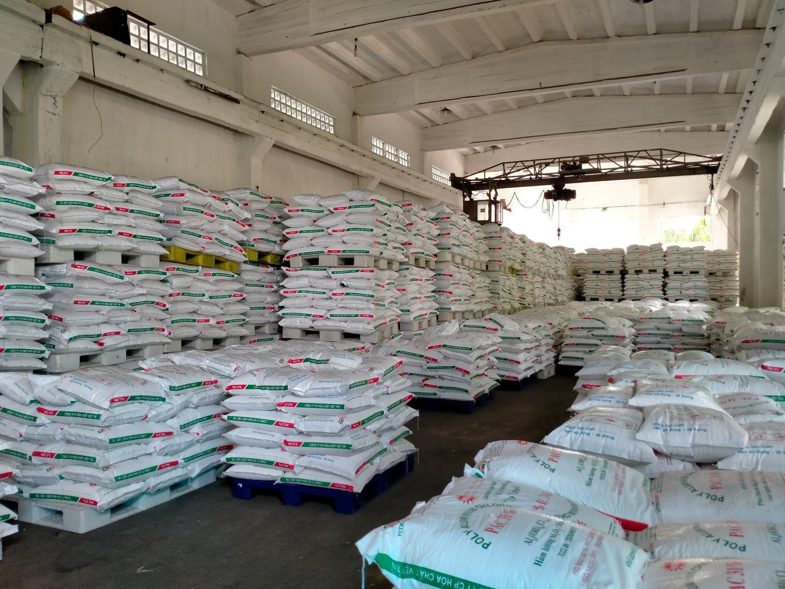 Kho nhà máy Vitrichem với hàng trăm bao PAC trắng xếp chồng trên pallet dưới mái nhà xưởng cao